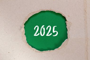 Yırtık kağıda yeşil arka planda 2025 adet mesaj yazıldı. Kavramsal 2025 sembolü. Boşluğu kopyala.