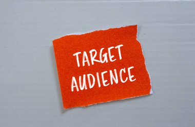 Gri arka planlı yırtık turuncu kağıt parçasına yazılmış hedef kitle mesajı. Kavramsal hedef kitle sembolü. Boşluğu kopyala.