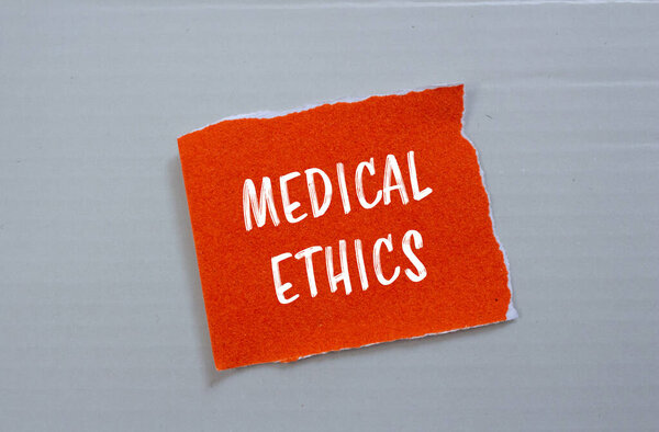 Медицинское этическое послание, написанное на разорванной оранжевой бумаге на сером фоне. Символ медицинской этики. Копирование пространства.