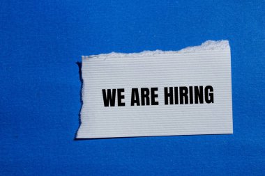 Mavi arkaplanlı, yırtık beyaz kağıt parçasına yazılmış kelimeleri işe alıyoruz. Kavramsal olarak sembol kiralıyoruz. Boşluğu kopyala.