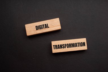 Siyah arkaplanlı tahta bloklara yazılmış dijital dönüşüm mesajı. Kavramsal dijital dönüşüm sembolü. Boşluğu kopyala.