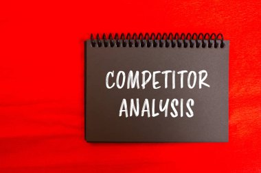 Rekabet analizi mesajı kırmızı arka planlı siyah defter sayfasına yazılmış. Kavramsal rakip analiz sembolü. Boşluğu kopyala.