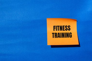 Turuncu kağıda mavi arkaplan ile yazılmış spor eğitimi mesajı. Kavramsal fitness eğitim sembolü. Boşluğu kopyala.