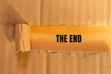 Yırtılmış, turuncu arka planlı karton kağıda yazılmış son mesaj. Son sembol kavramsal. Boşluğu kopyala.