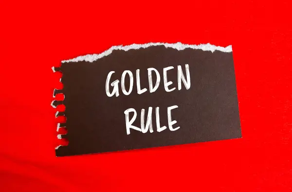 stock image Golden rule message written on ripped torn black paper piece with red background. Conceptual golden rule symbol. Copy space.