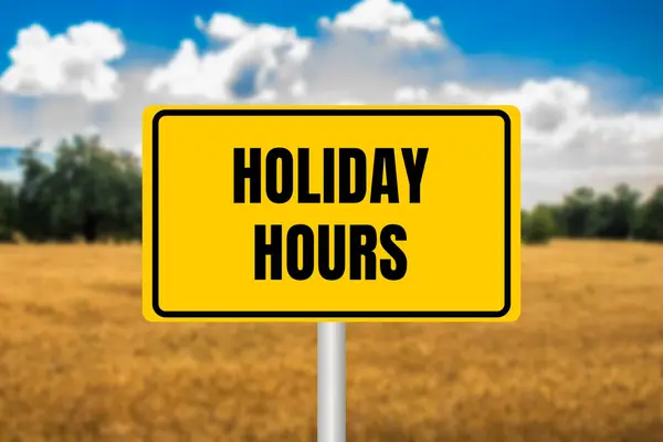 stock image Holiday hours message written on yellow metal sign on blurry wheat field background. Conceptual holiday hours symbol. Copy space.