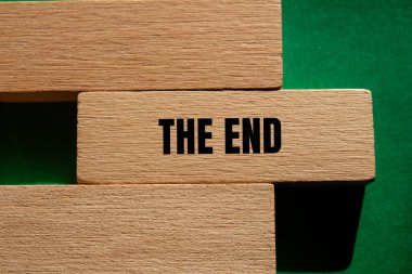 Tahta blokta yeşil arka planda yazılmış son mesaj. Son sembol kavramsal. Boşluğu kopyala.