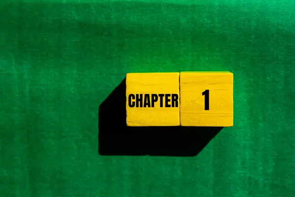 stock image Chapter 1 message written on yellow wooden cubes with green background. Conceptual chapter 1 symbol. Copy space.