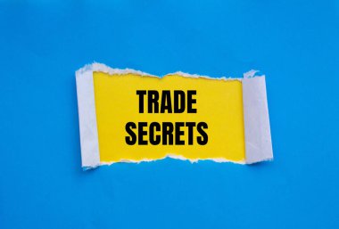 Sarı arka planlı yırtık mavi kağıda yazılmış ticari sırlar mesajı. Kavramsal ticaret sırları sembolü. Boşluğu kopyala.