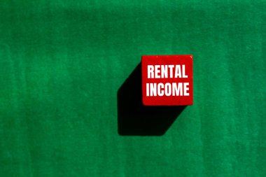 Kiralık gelir mesajı yeşil arka planlı kırmızı tahta küpte yazılmış. Kavramsal kiralama gelir sembolü. Boşluğu kopyala.