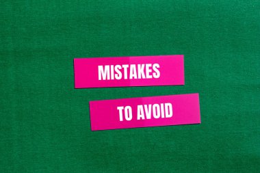 Mistakes to avoid message written on pink paper with green background. Conceptual mistakes to avoid symbol. Copy space. clipart