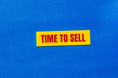 Time to sell message written on yellow sticker with blue background. Conceptual time to sell symbol. Copy space. clipart