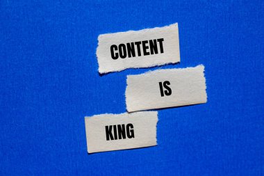 Content is king message written on ripped torn paper peices with blue background. Conceptual content is king symbol. Copy space.