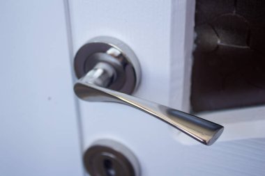 Beyaz ahşap bir kapının metal kapı kolu, yakın plan.