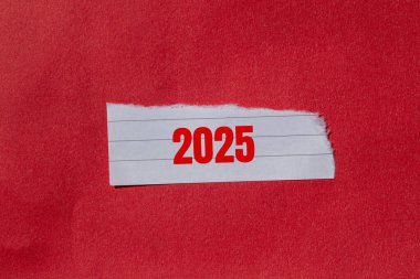 Yırtık kağıt parçasına kırmızı arkaplanlı 2025 adet mesaj. Kavramsal 2025 sembolü. Boşluğu kopyala.