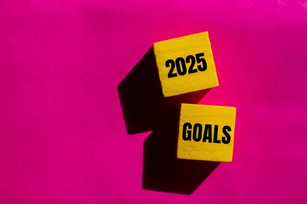 2025 gol mesajı pembe arkaplanlı sarı tahta küplere yazılmış. Kavramsal 2025 hedef sembolü. Boşluğu kopyala.