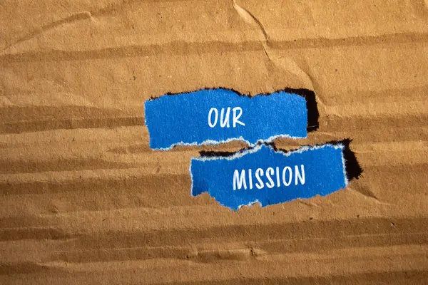 stock image Our mission message written on ripped blue paper pieces with cardboard background. Conceptual our mission symbol. Copy space.