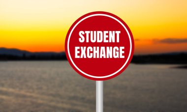 Student exchange message written on red sign on blurry lake background at sunset. Conceptual student exchange symbol. Copy space.