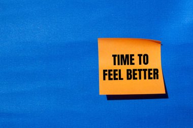 Time to feel better message written on orange paper with blue background. Conceptual time to feel better symbol. Copy space. clipart