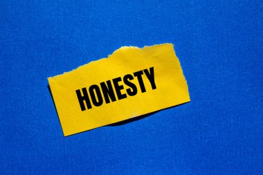 Honesty message written on ripped torn yellow paper piece with bluebackground. Conceptual honesty symbol. Copy space. clipart