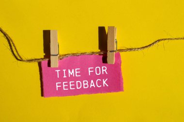 Sarı arkaplanlı pembe kağıt parçasına geri bildirim yazma zamanı. Geri bildirim sembolü için kavramsal zaman. Boşluğu kopyala.