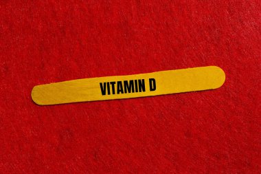 Kırmızı arka planlı sarı tahta çubuğa yazılmış D vitamini mesajı. Kavramsal D vitamini sembolü. Boşluğu kopyala.