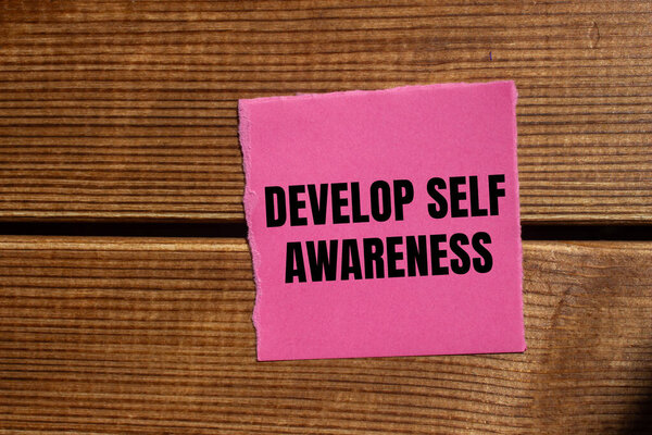 Разработайте сообщение самосознания, написанное на разорванной розовой бумаге кусок с деревянным фоном. Концептуальное развитие самосознания символ. Копирование пространства.