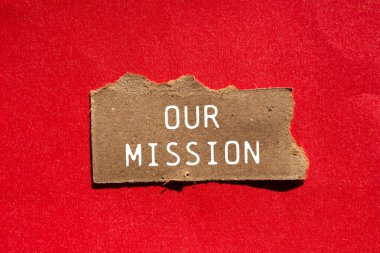 Görev mesajımız kırmızı arka plandaki yırtık kahverengi kağıt parçasına yazılmış. Görevimizin sembolü kavramsal. Boşluğu kopyala.