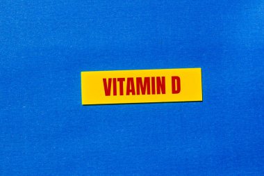 Mavi arka planlı sarı etikete D vitamini mesajı yazılmış. Kavramsal D vitamini sembolü. Boşluğu kopyala.