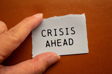 Kahverengi arka planda yırtık kağıt parçasına yazılan kriz mesajı. İlerideki kavramsal kriz sembolü. Boşluğu kopyala.