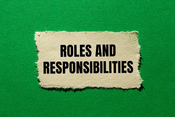 Сообщение о ролях и обязанностях, написанное на разорванной бумаге на зеленом фоне. Символ концептуальных ролей и обязанностей. Копирование пространства.