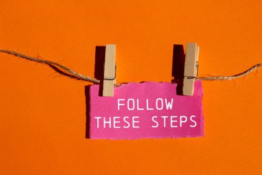 Turuncu arka planda pembe yırtık kağıt parçasına yazılmış bu mesajları takip et. Kavramsal olarak bu adımları takip et. Boşluğu kopyala.