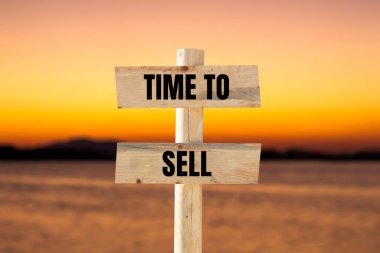 Time to sell message written on wooden sign with blurry lake background. Conceptual time to sell symbol. Copy space. clipart