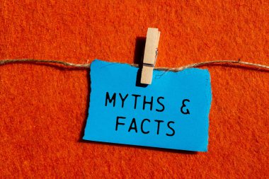 Efsaneler ve gerçekler turuncu arka plandaki yırtık mavi kağıt parçasına yazılmış. Kavramsal mitler ve gerçekler sembolü. Boşluğu kopyala.