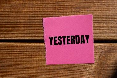 Ahşap kapaklı, yırtık pembe kağıt parçasına dün yazılmış bir mesaj. Kavramsal dünün sembolü. Boşluğu kopyala.