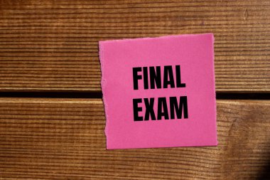 Tahta arka planda yırtık pembe kağıt parçasına yazılmış son sınav mesajı. Kavramsal nihai sınav sembolü. Boşluğu kopyala.