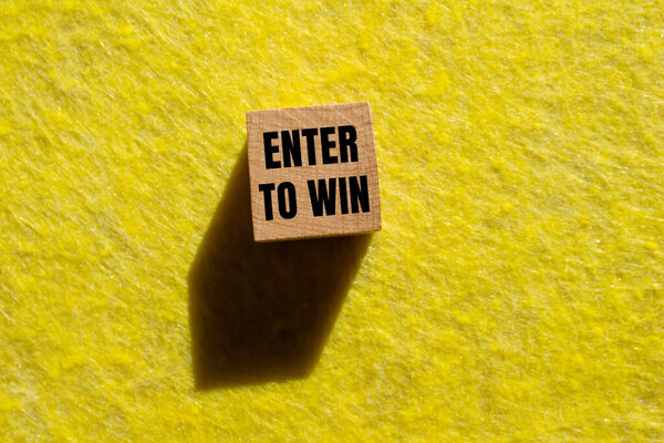 Enter to win message written on wooden cube with yellow background. Conceptual enter to win symbol. Copy space.