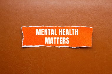 Zihinsel sağlık sorunları mesajı yırtık turuncu kağıt parçasına yazılmış kahverengi arkaplanlı. Kavramsal zihinsel sağlık meseleleri sembolü. Boşluğu kopyala.