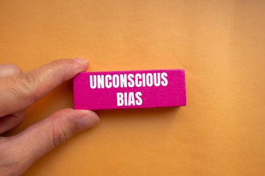 Unconscious bias message written on pink wooden block with orange background. Conceptual unconscious bias symbol. Copy space. clipart