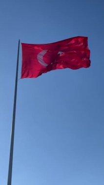 Türk bayrağı açık mavi gökyüzüne karşı rüzgarda dalgalanıyor