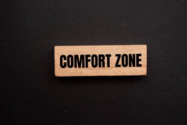 Comfort zone message written on wooden block with black background. Conceptual comfort zone symbol. Copy space. clipart