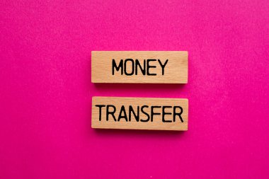 Tahta bloklara pembe arka planlı para transferi mesajı yazıldı. Kavramsal para transfer sembolü. Boşluğu kopyala.