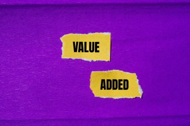 Value added message written on ripped torn yellow paper pieces with purple background. Conceptual value added symbol. Copy space. clipart