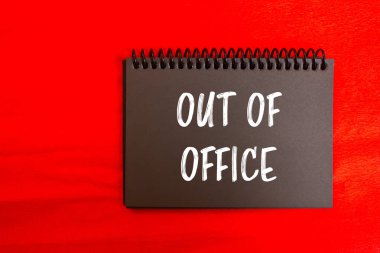 Ofis dışı mesajı kırmızı arkaplanlı siyah defter sayfasına yazılmış. Ofis dışında kavramsal bir sembol. Boşluğu kopyala.