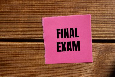 Tahta arka planda yırtık pembe kağıt parçasına yazılmış son sınav mesajı. Kavramsal nihai sınav sembolü. Boşluğu kopyala.