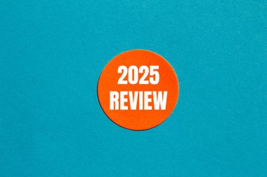 2025 review message written on round orange sticker with blue background. Conceptual 2025 review symbol. Copy space. clipart