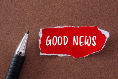Yırtık kırmızı kağıt parçasına ve kahverengi arka planı olan bir kaleme iyi haber mesajı. Kavramsal iyi haber sembolü. Boşluğu kopyala.