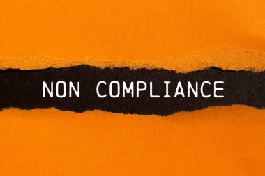 Non compliance message written on ripped torn orange paper with black background. Conceptual non compliance symbol. Copy space. clipart