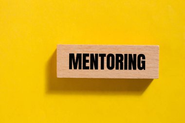 Ahşap blokta sarı arka planda yazılmış akıl hocalığı mesajı. Kavramsal akıl hocalığı sembolü. Boşluğu kopyala.