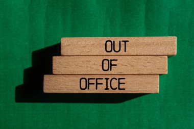 Tahta bloklara yeşil arkaplan ile yazılmış ofis dışı mesajlar. Ofis dışında kavramsal bir sembol. Boşluğu kopyala.